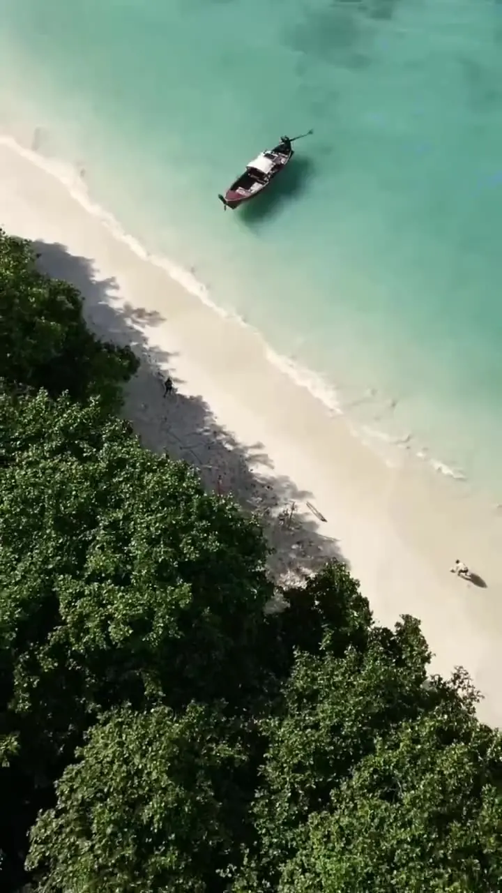 A longtail boat on turquoise water seen from above