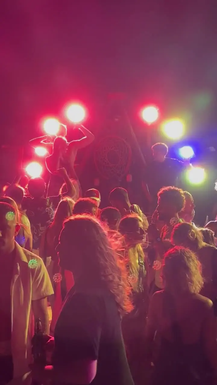 Crowd in front of a DJ with coloured lights